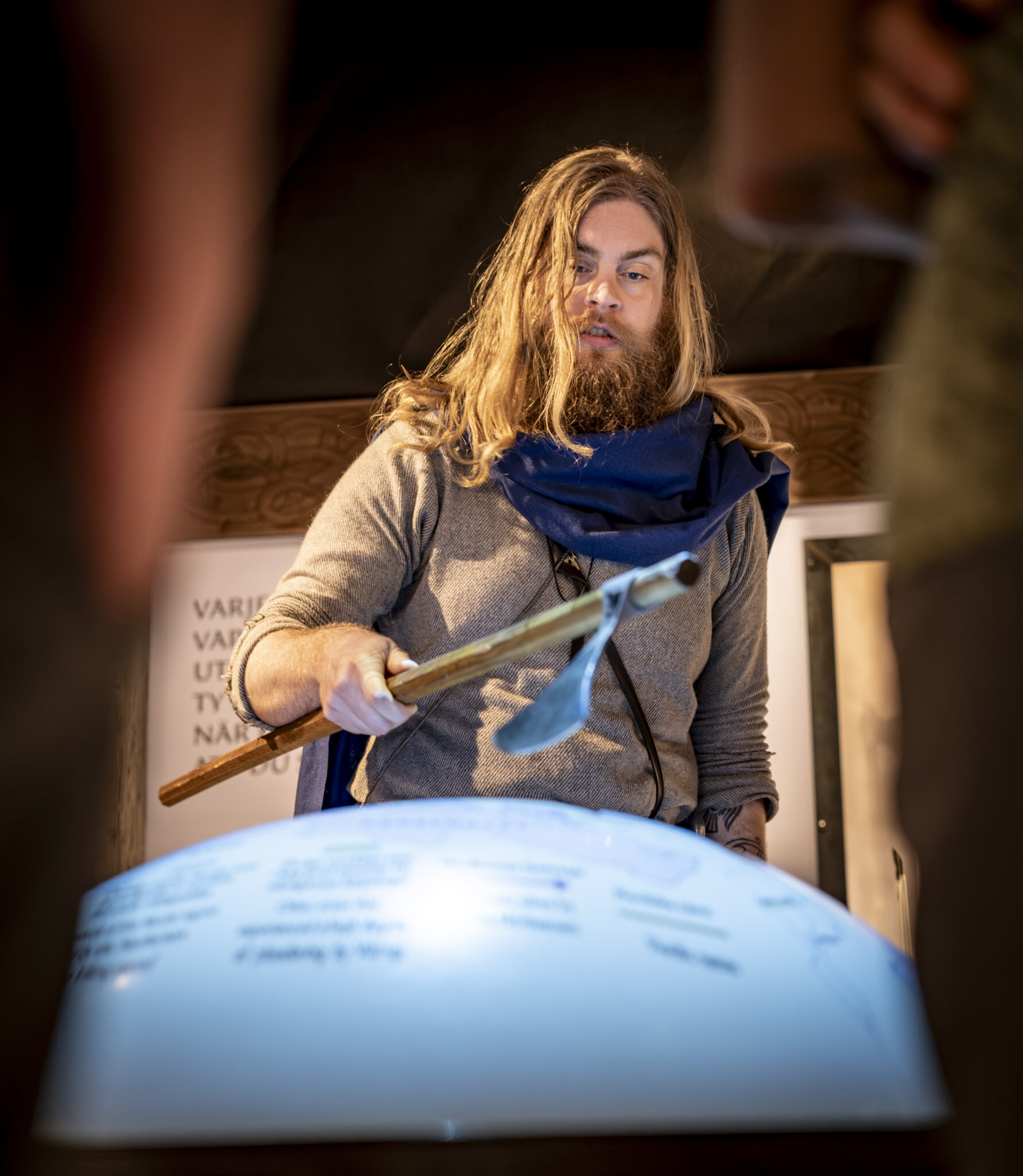 A tour guide dressed in Viking costume and standing next to an interactive globe in the exhibition.