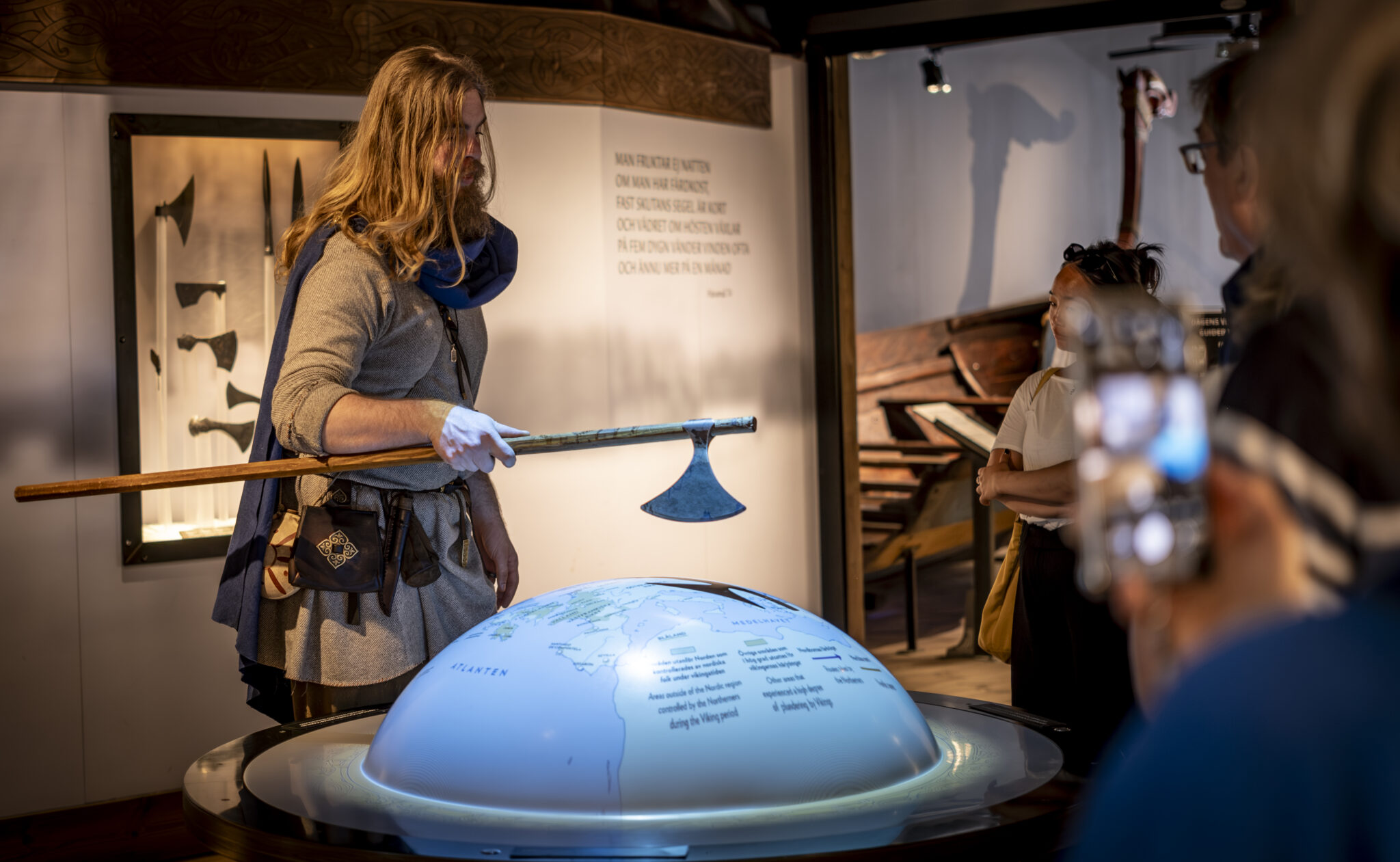 A tour guide dressed in Viking costume and showing an interactive map to visitors in the exhibition.