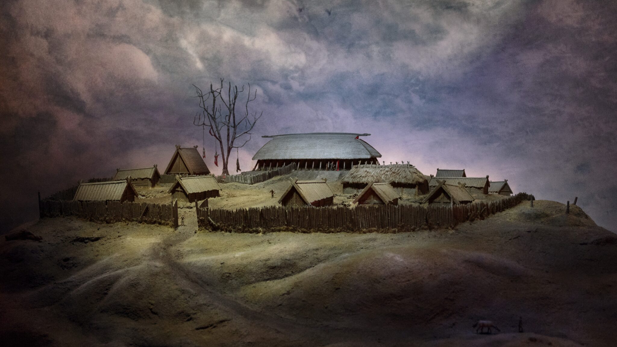 En gård från vikingatiden med flera mindre hus och ett större och grönområde runtomkring.