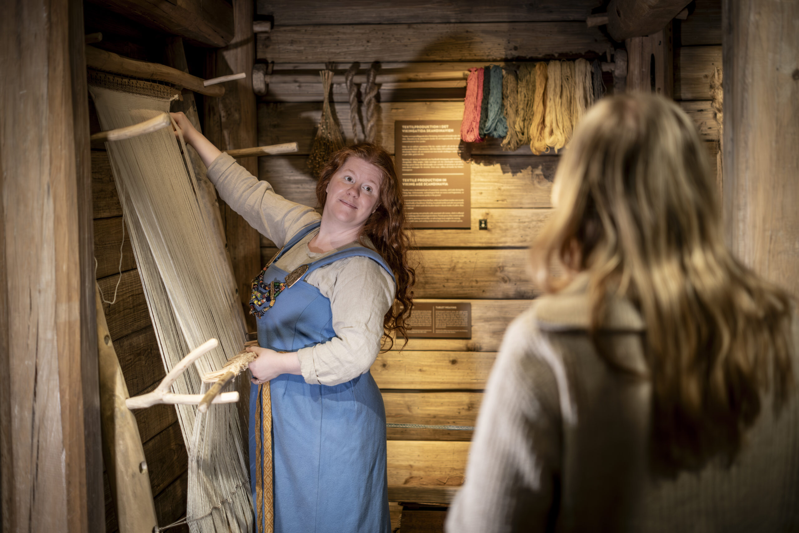 En guide i vikingakläder hanterar vävstol