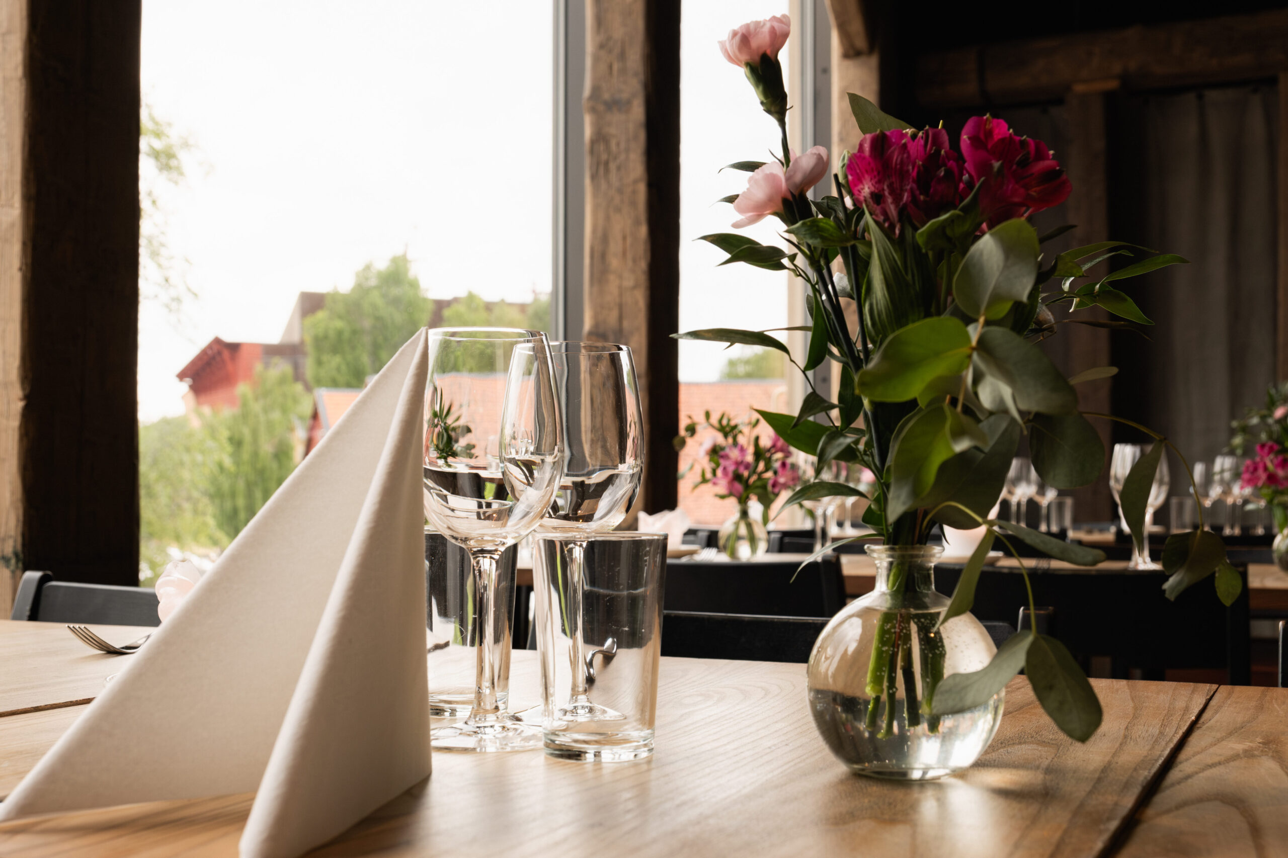 nside, a wooden table is beautifully set in a restaurant with a view.