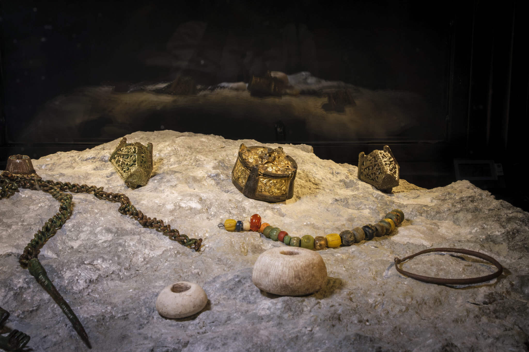 Personal items such as necklaces and rings displayed on a stone.
